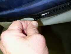 Hand unzipping the top cover of a low air loss mattress to expose the air bladders